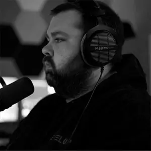Black-and-white side-profile portrait of Joshua Garr wearing studio headphones and speaking into a microphone.