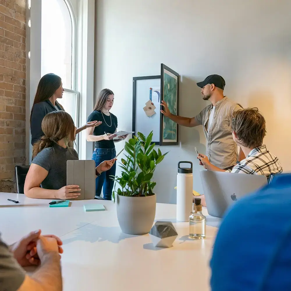 Small team collaborating around a table during a business meeting in a bright modern workspace.